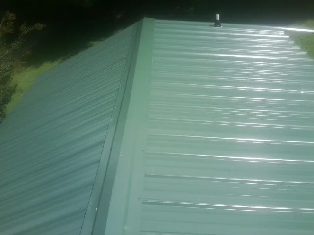 New green metal panels meeting at the ridge of a roof — Flat Roof Repair work by our crew in Morral