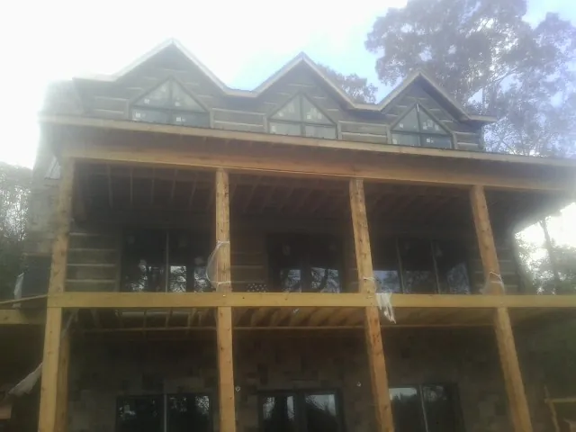 Dormers and porch framing on a large log home under construction — Roof Coating work by our crew in Morral