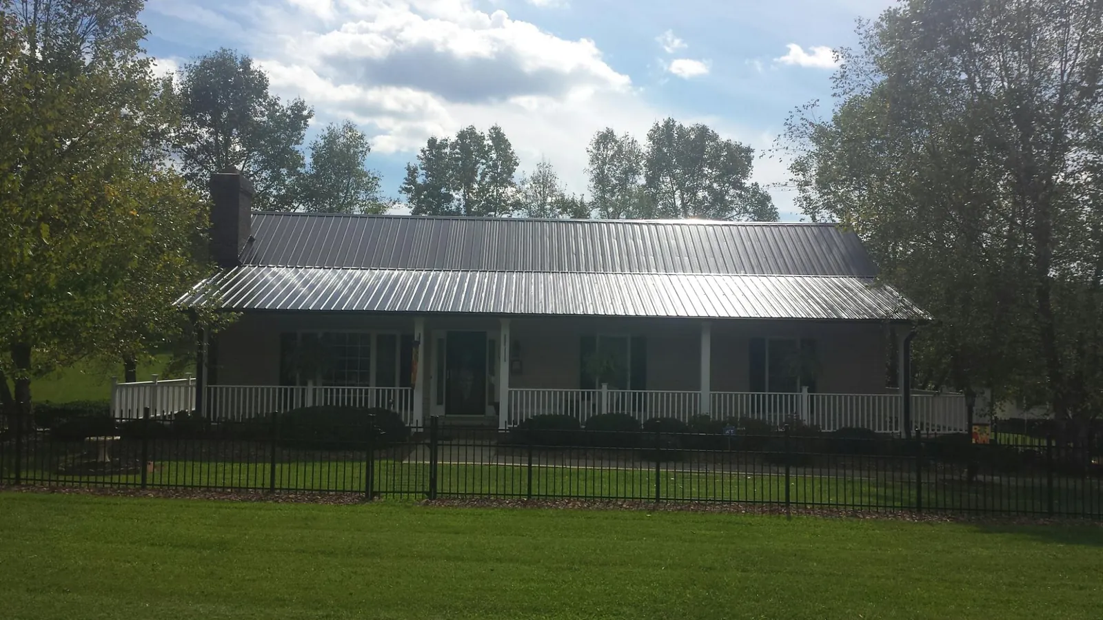 Gray metal roof on a brick ranch with a full width front porch — Gutter Guard Installation work by our crew in Morral