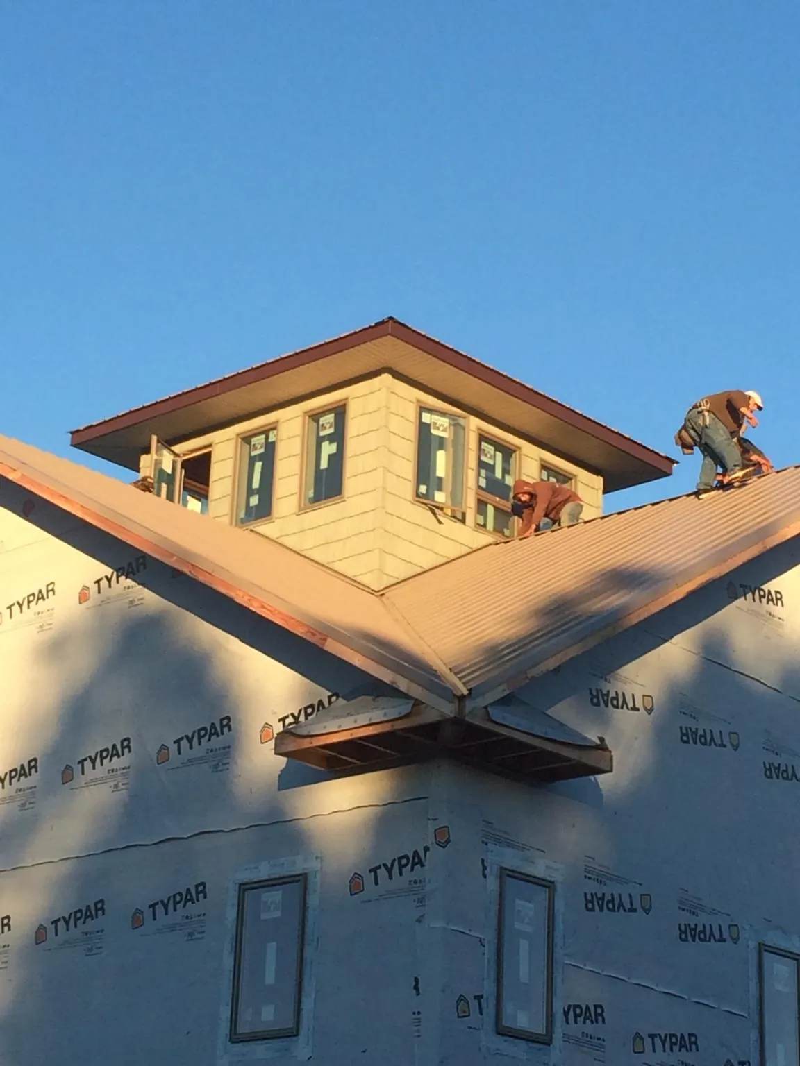 Roofers working around a rooftop cupola on a new metal roof at sunset — Roof Waterproofing in Morral by Roofing Brothers